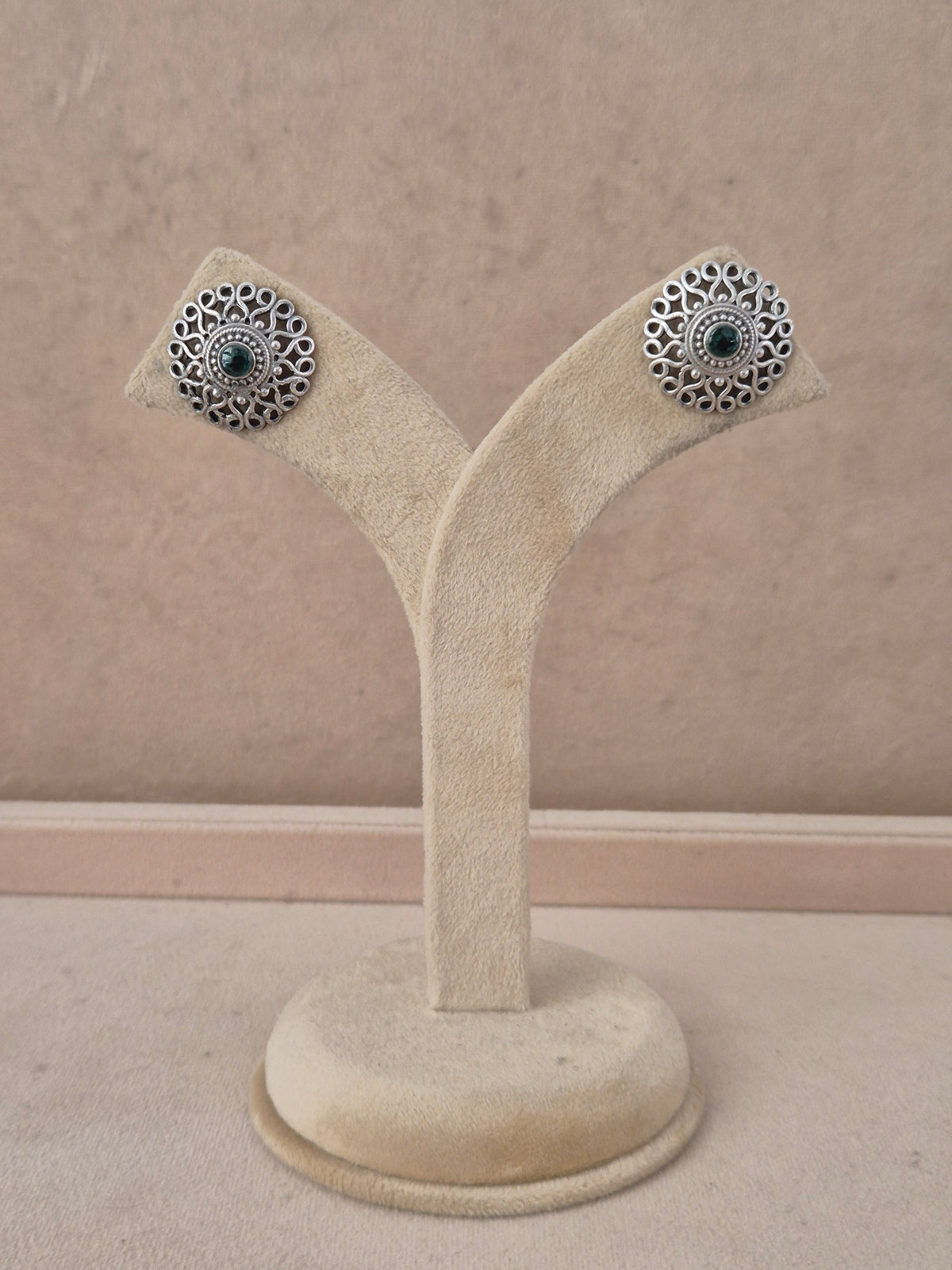 A pair of silver-toned filigree stud earrings with dark green stone centers, by naitri.in