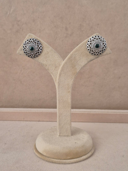 A pair of silver-toned filigree stud earrings with dark green stone centers, by naitri.in