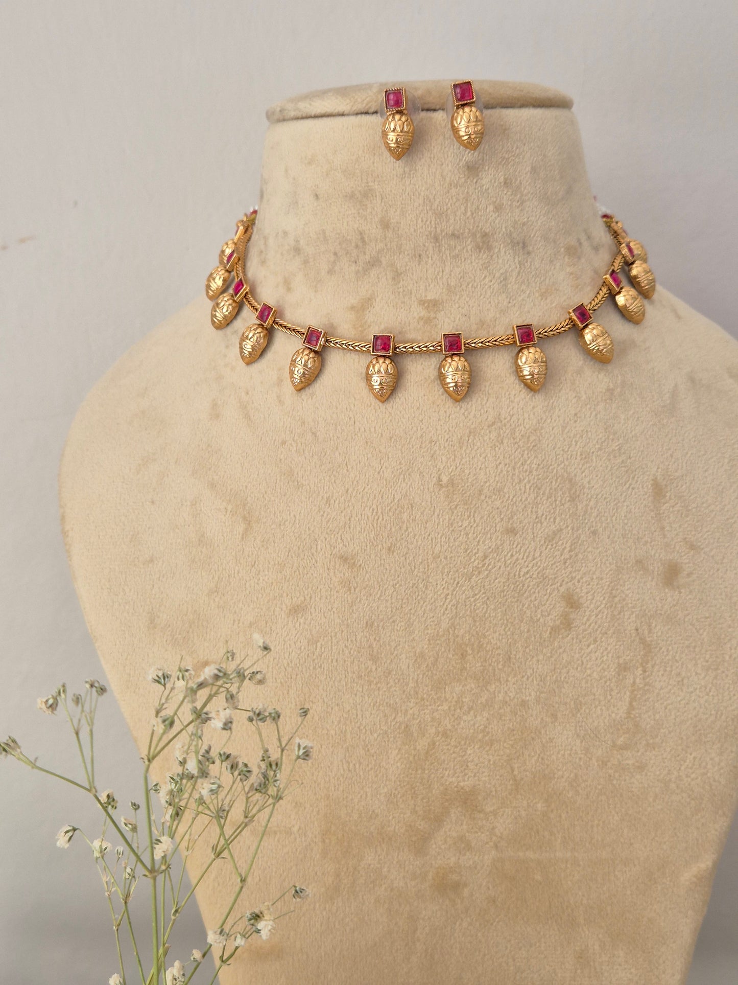 Gold-toned necklace and matching earrings with small red rectangular stones, by naitri.in