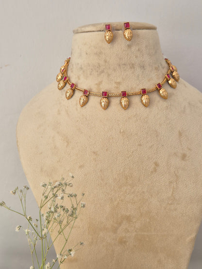 Gold-toned necklace and matching earrings with small red rectangular stones, by naitri.in
