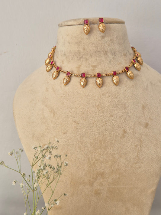 Gold-toned necklace and matching earrings with small red rectangular stones, by naitri.in