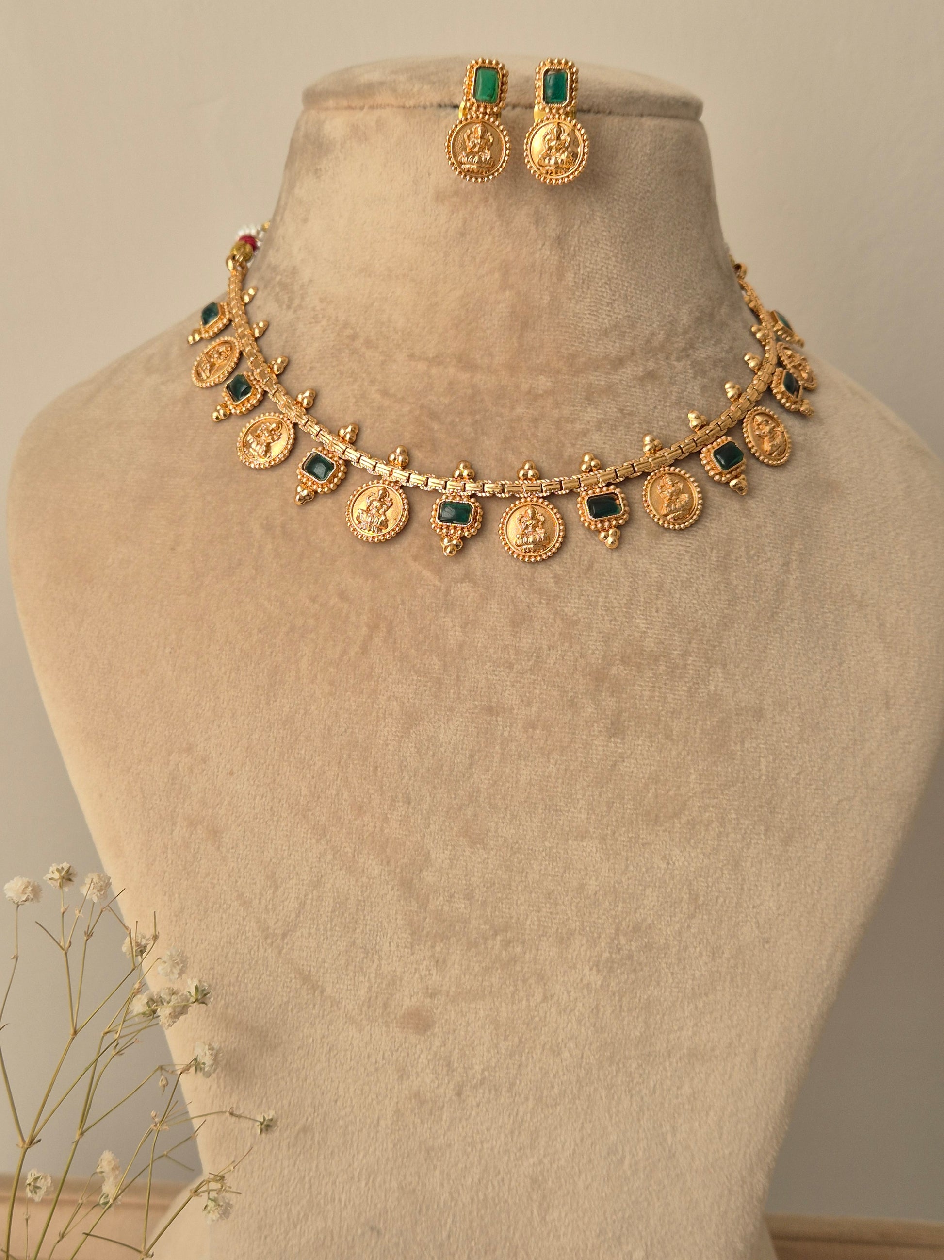 Gold necklace with green coin designed  Naitri on bust form by naitri.in