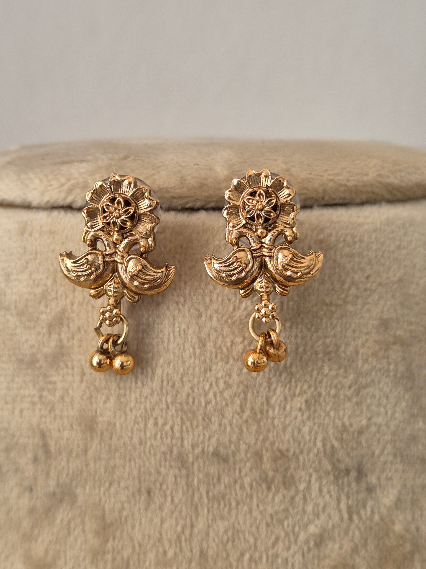 A pair of gold-toned traditional Indian jhumka earrings with floral and bird motifs, by naitri.in