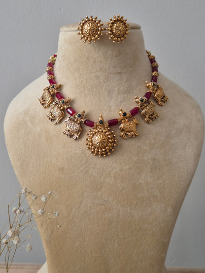 Set featuring gold-toned temple jewelry with bird motifs, red beads, and matching circular stud earrings by naitri.in