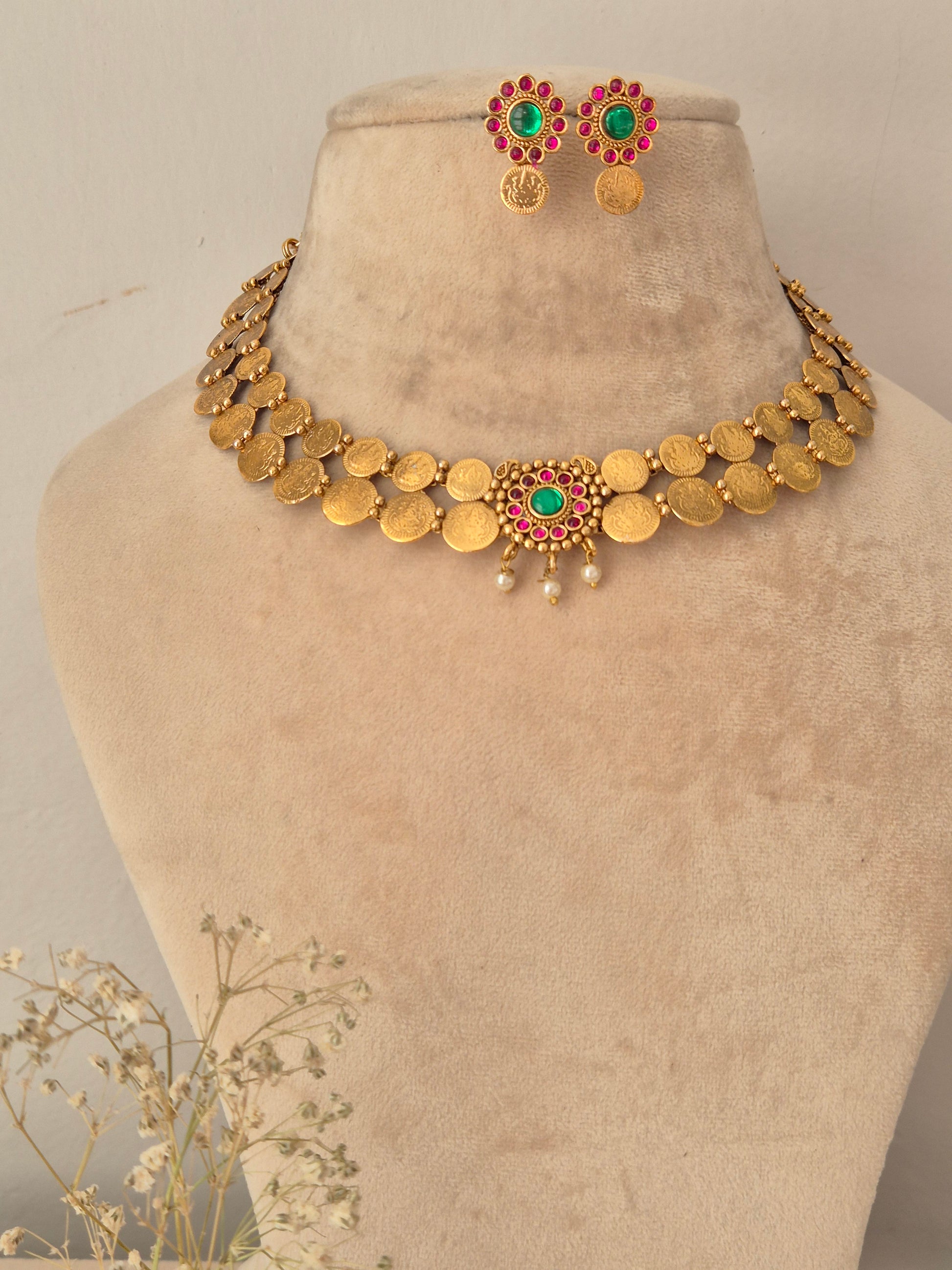 Gold-tone ethnic short necklace set with red and green stones, pearl clusters, and matching circular stud earrings Festive antique gold-plated coin necklace set by naitri.in