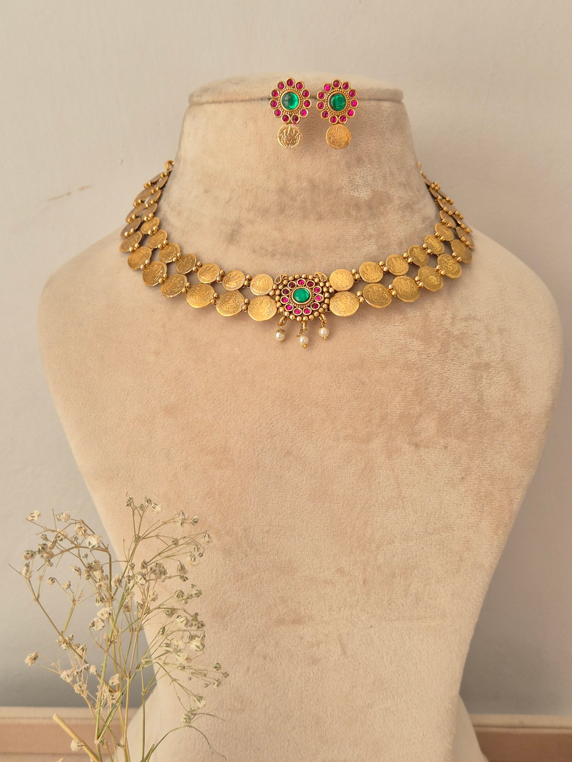 Gold-tone ethnic short necklace set with red and green stones, pearl clusters, and matching circular stud earrings by naitri.in
