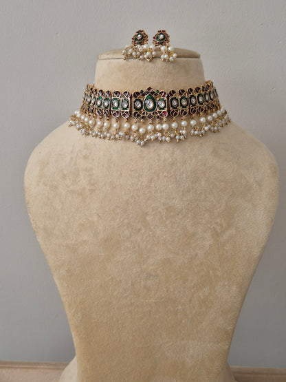 Handcrafted set featuring a central green stone, ruby pink accents, and a fringe of white pearl droplets,  with matching stud earrings by naitri.in