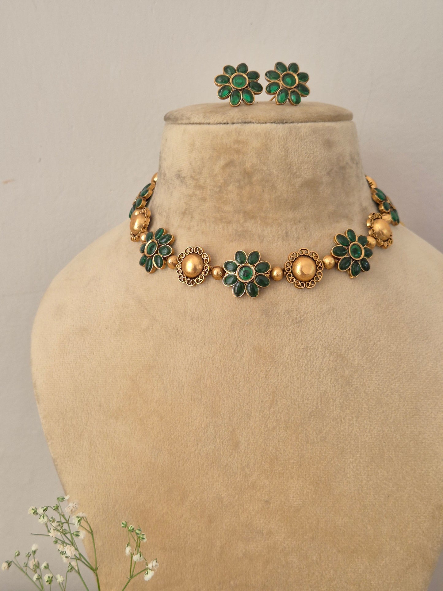 Elegant green gemstone and gold-toned traditional choker jewelry set, Gold-plated choker necklace with green floral gemstones and matching stud earrings by naitri.in 