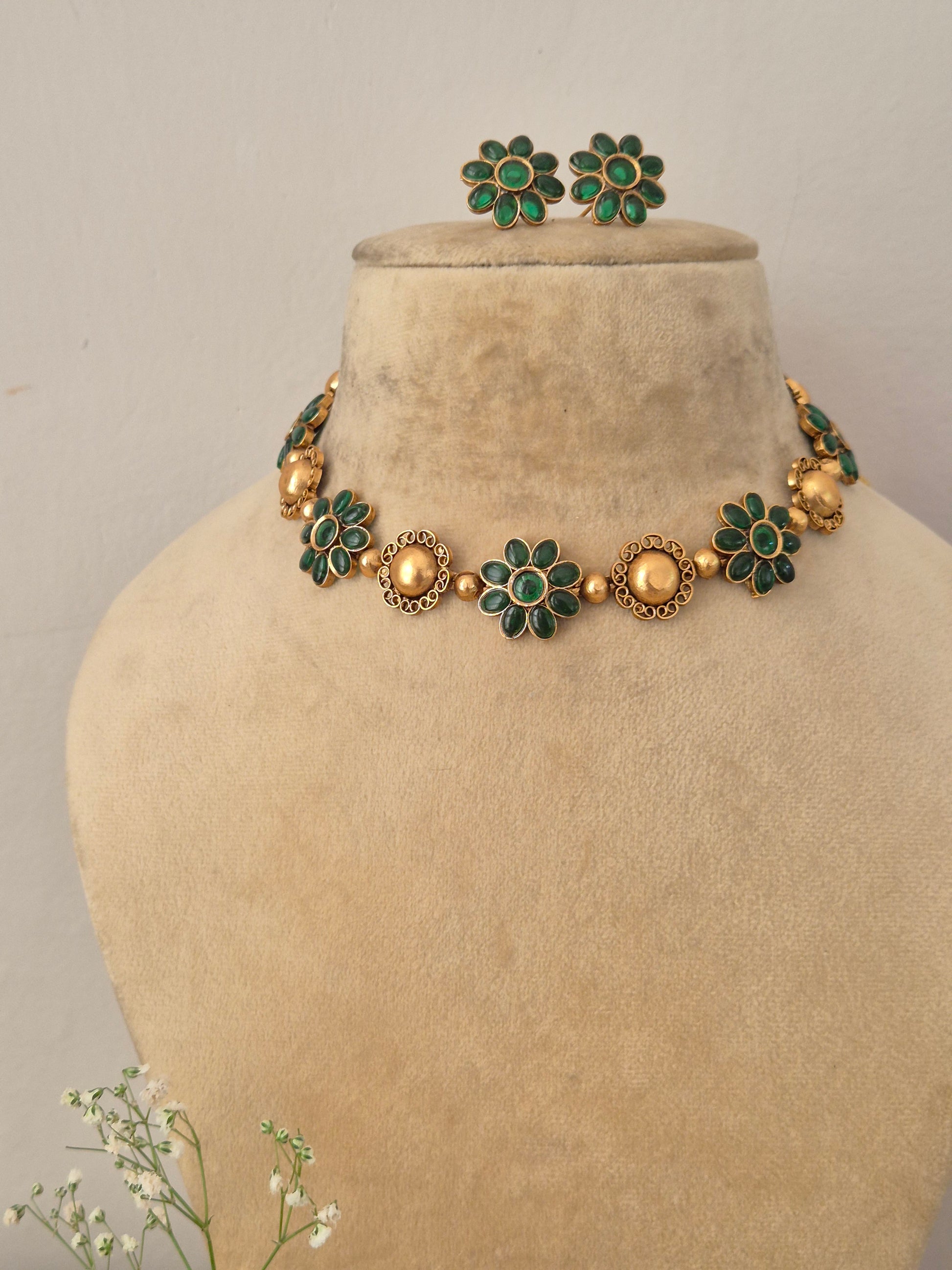 Elegant green gemstone and gold-toned traditional choker jewelry set, Gold-plated choker necklace with green floral gemstones and matching stud earrings by naitri.in 