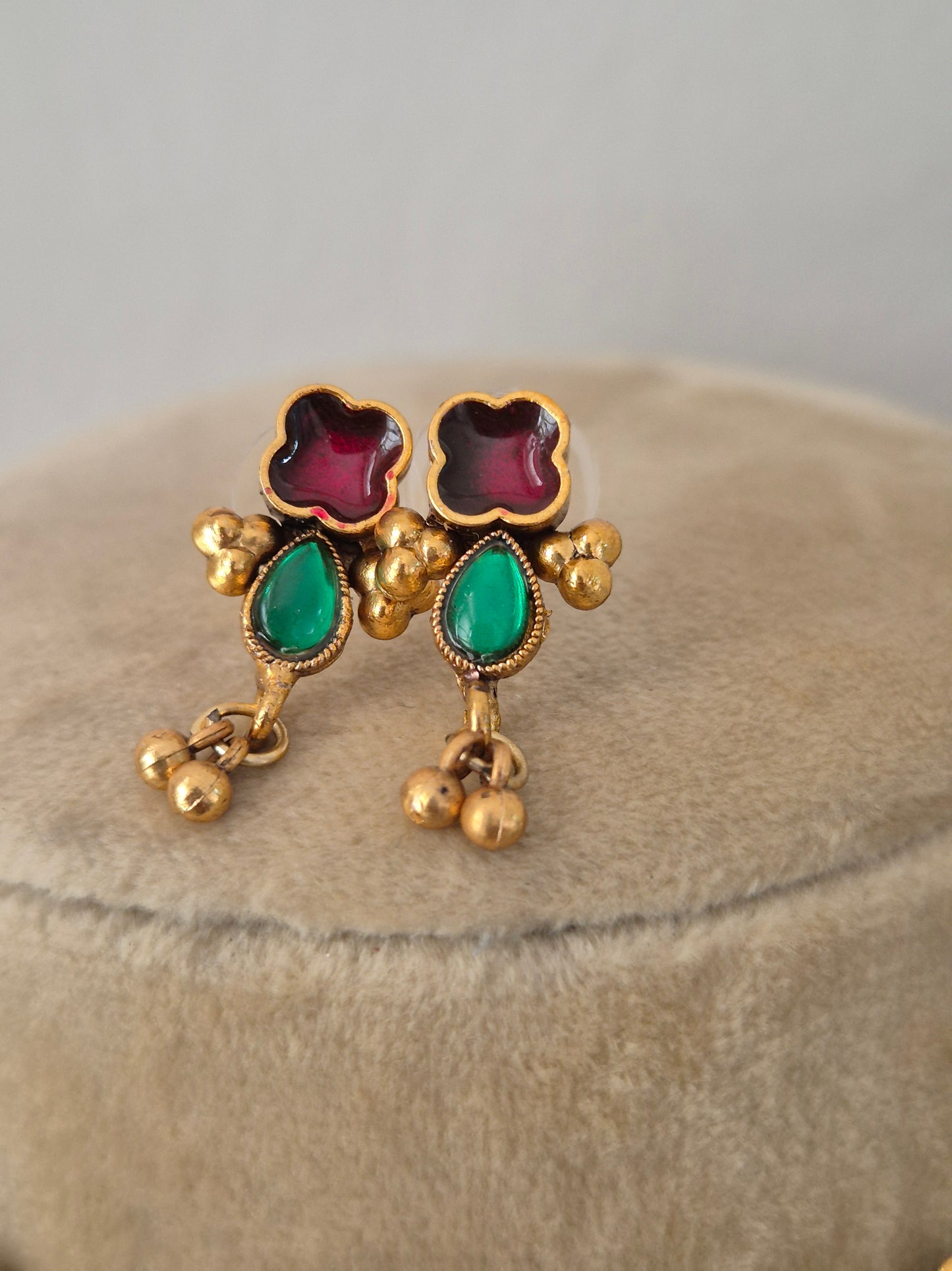 Gold-plated earring embedded with ruby red and emerald green stones, and gold hangings by naitri.in