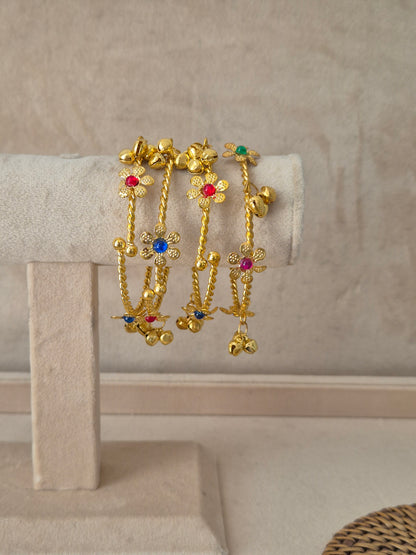 Set of 4 gold Geetanjali bangles with multi-colored floral gemstones and hanging ghungroo chains. Elegant golden ethnic bracelets with traditional festive details and hanging accents by naitri.in