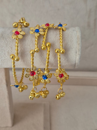 Statement gold bridal bangle set featuring intricate hand-painted floral panels, multi-color round stone settings, and delicate dangling metallic bell clusters by naitri.in