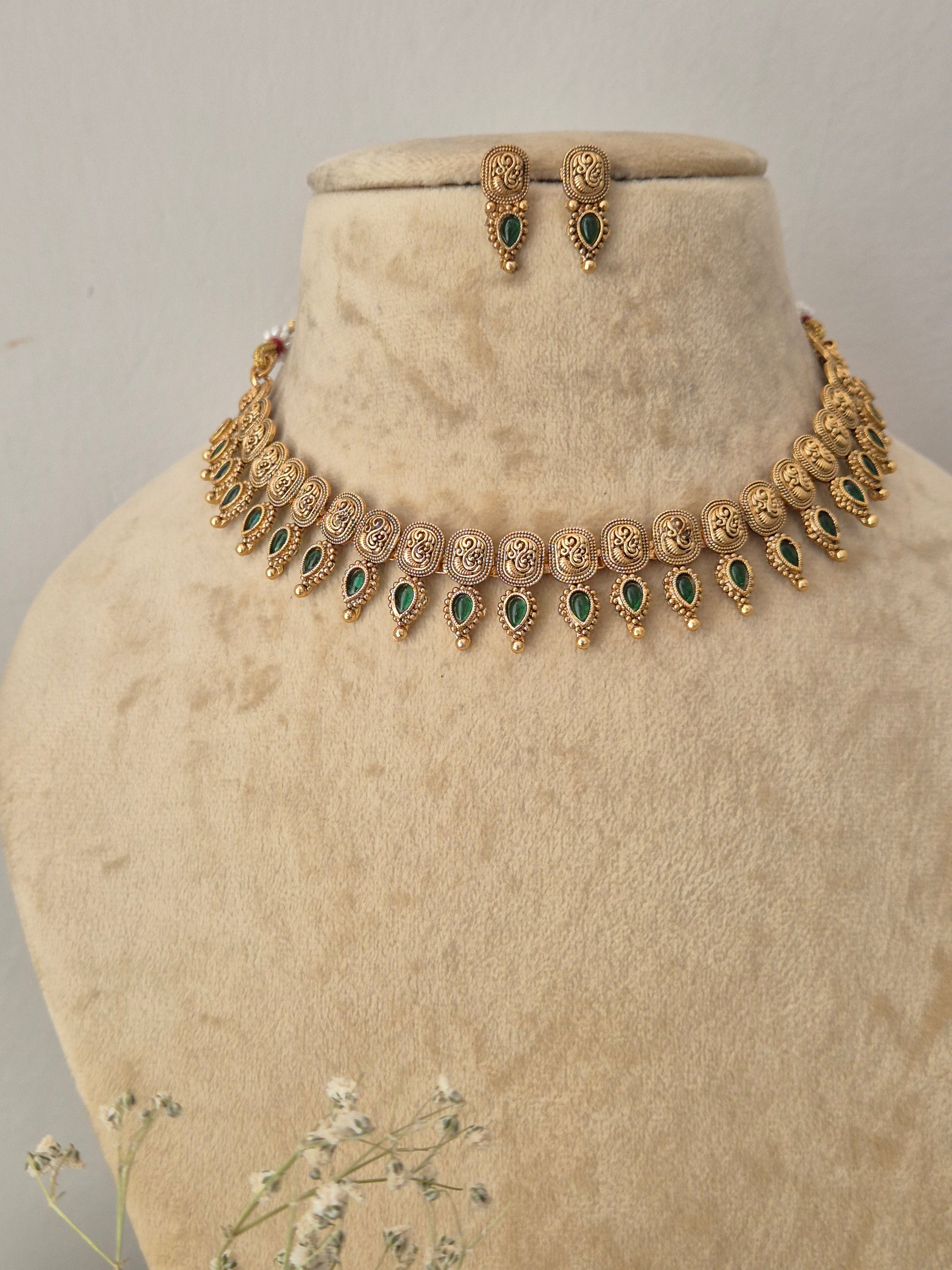 Gold-toned traditional jewelry set featuring a necklace and matching earrings with green stone accents, for festive wear by naitri.in