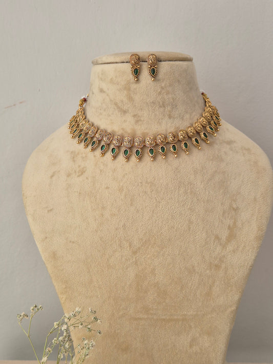 Gold-toned traditional Indian choker necklace and matching small dangle earrings set the necklace features intricate metalwork patterns with a lower fringe of delicate hanging green gemstone drops, by naitri.in