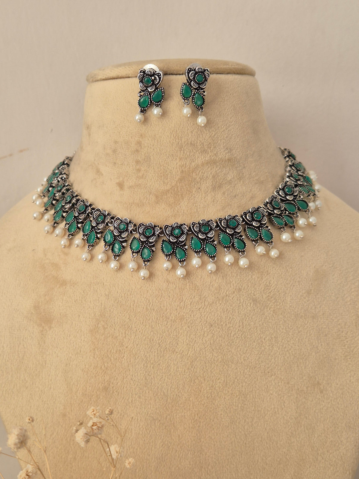 Pair of oxidized silver floral motif choker necklace with matching green stone earrings by Naitri.in