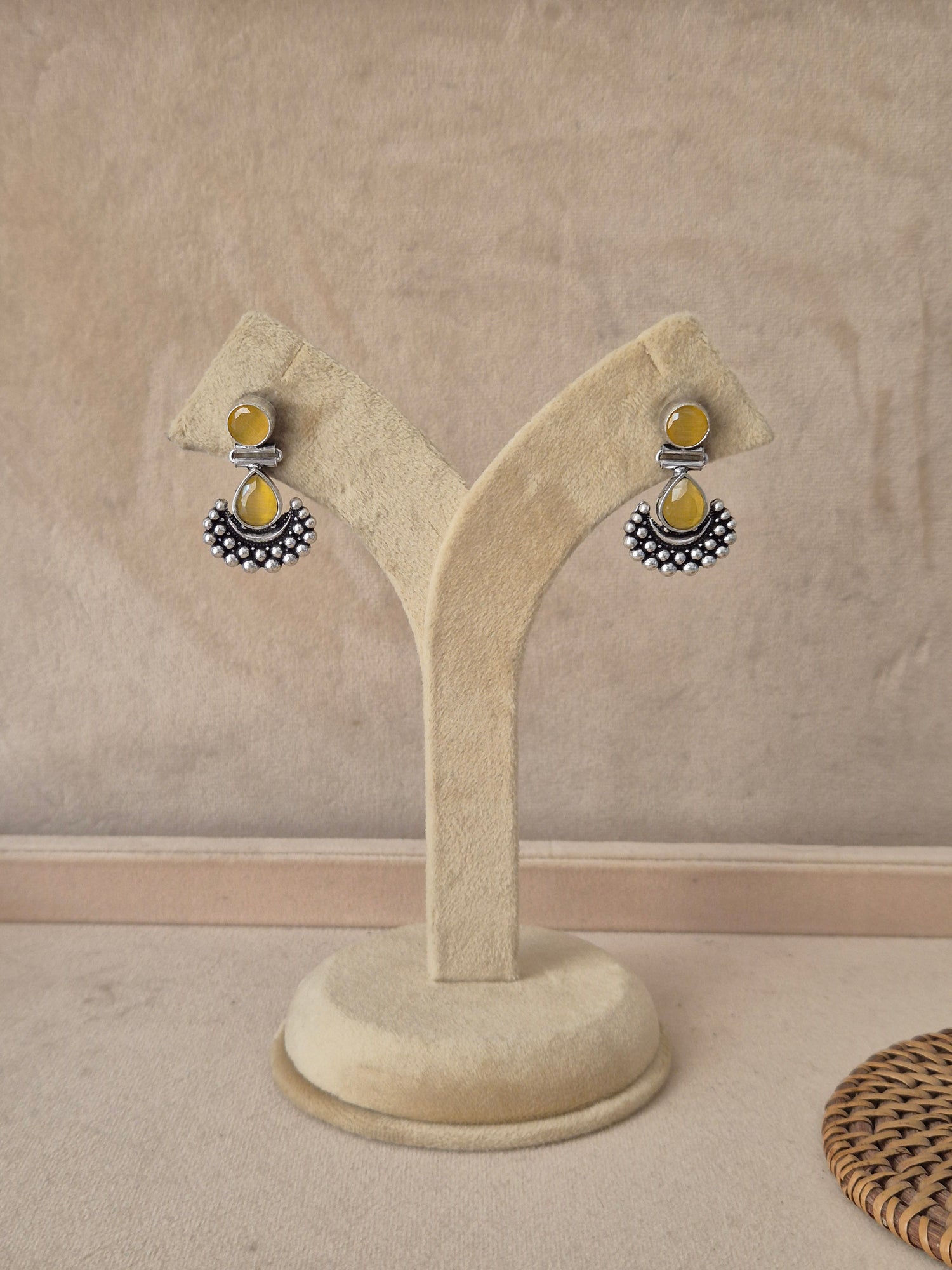 Pair of Grishma silver-toned dangle earrings featuring translucent yellow stone drops and a textured crescent accent by naitri.in