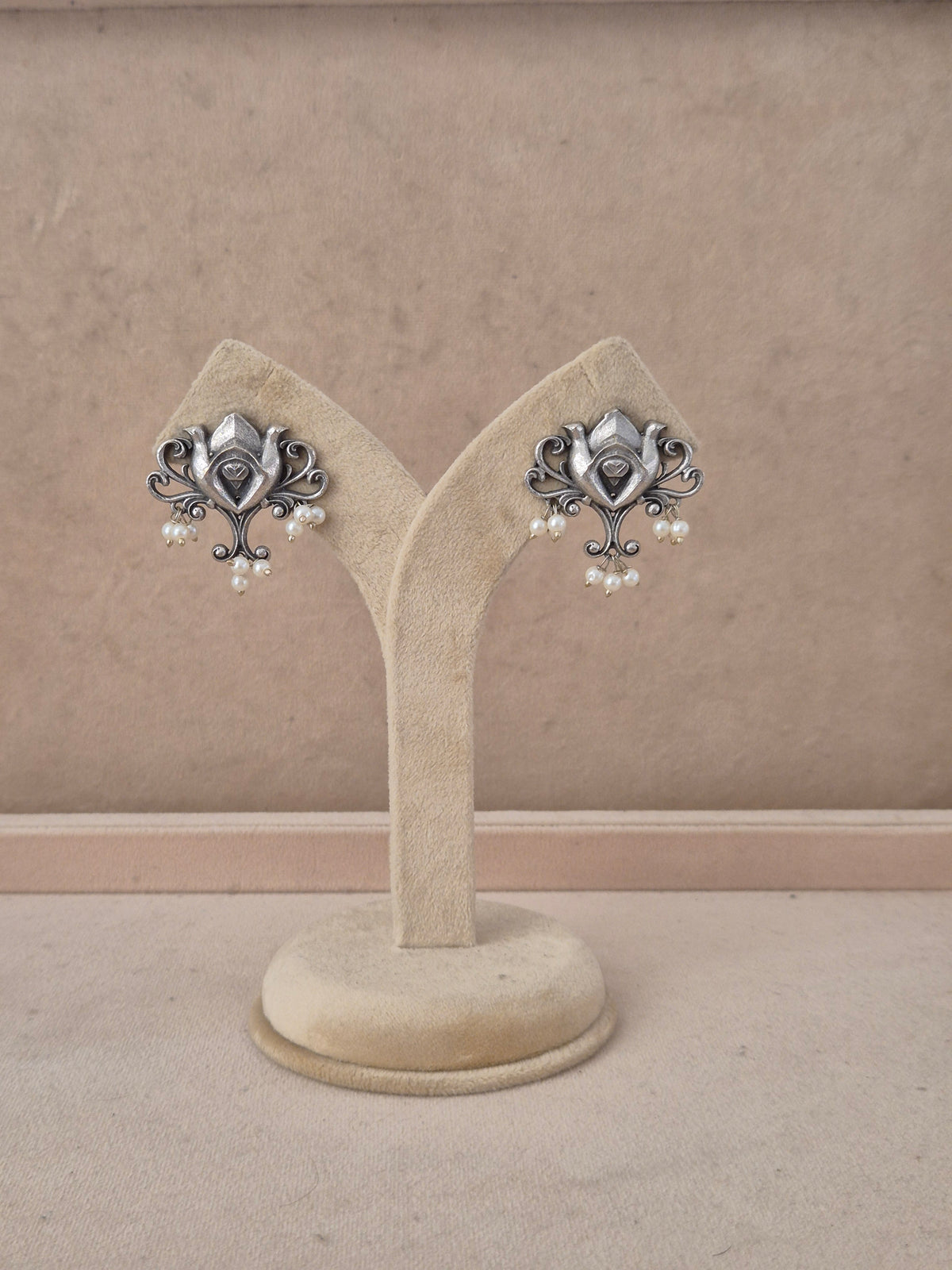 A pair of ornate silver-toned earrings with dangling pearl clusters, by naitri.in