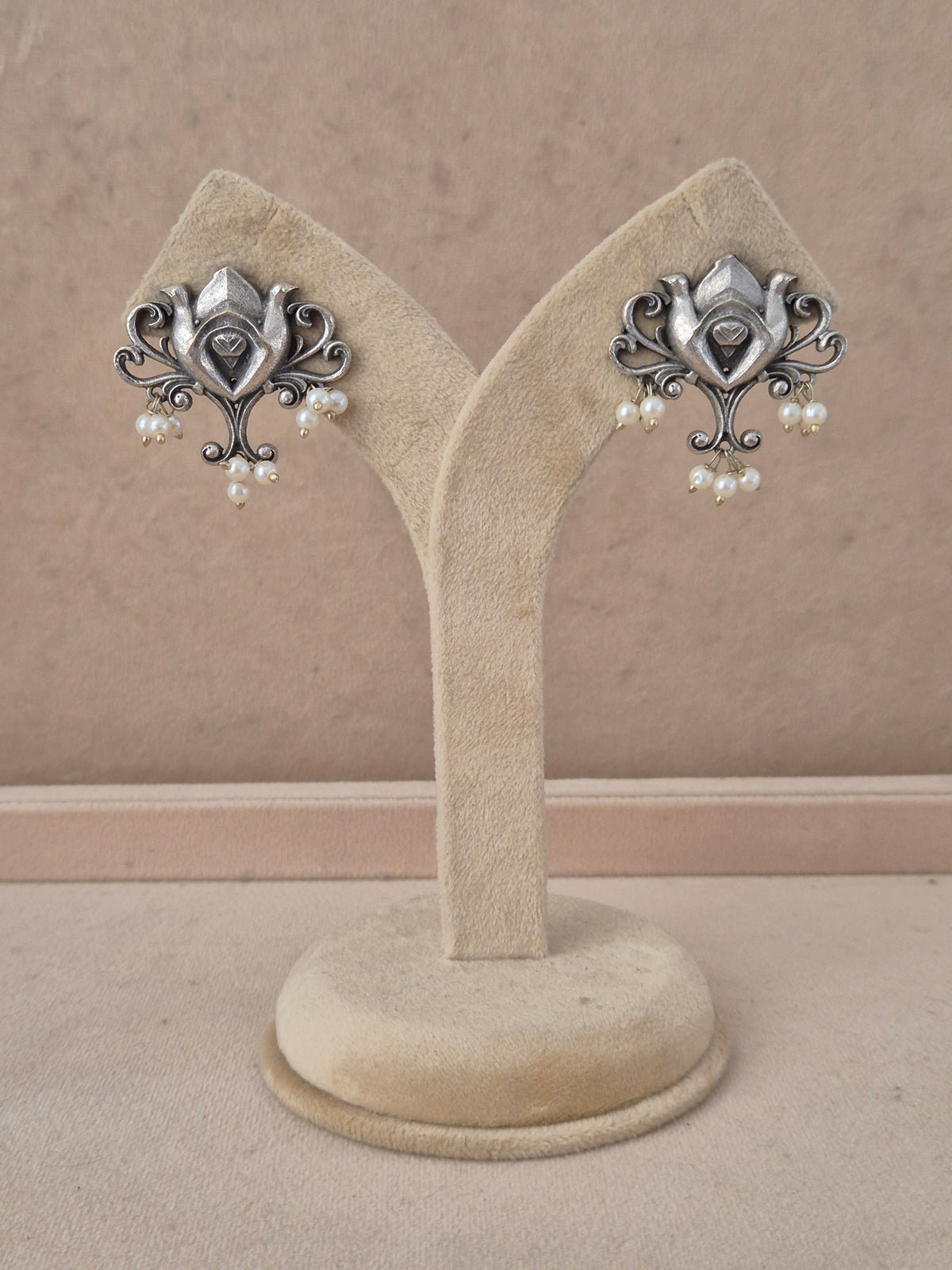 A pair of ornate silver-toned earrings with small white pearl drops, by naitri.in