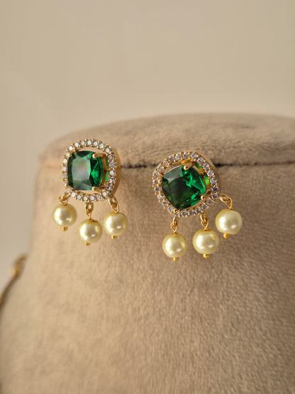 Pair of earrings with green gemstones and pearl-like beads and rinestone in the side of green emerald by naitri.in