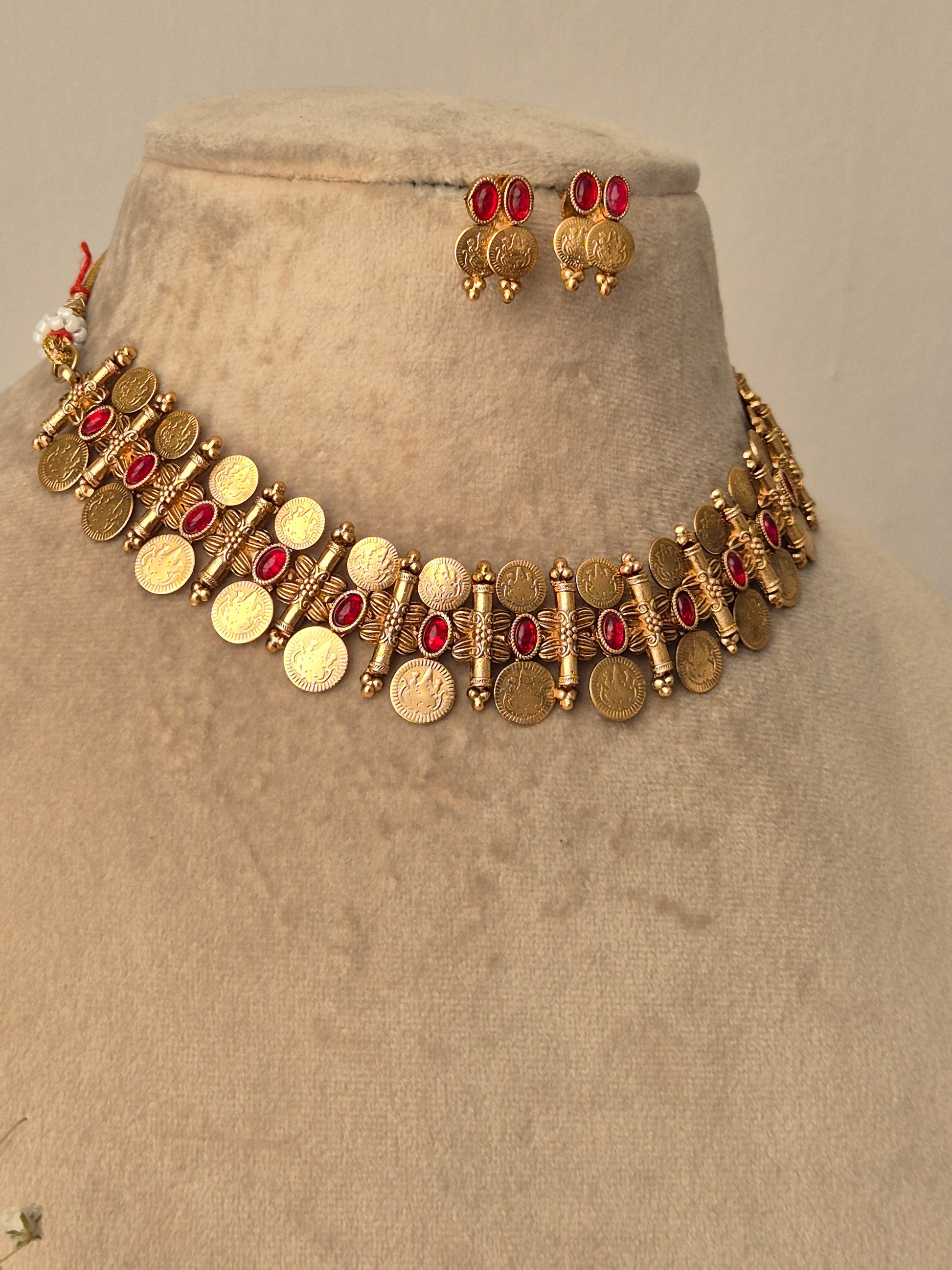 Handcrafted Pooja gold-tone choker set with red stone accents and dangling metallic coins, circular gold coin drops with matching ethnic earrings by naitri.in