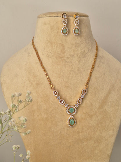 Handcrafted brass alloy necklace set with a polished gold finish and shimmering synthetic green stone embellishments.