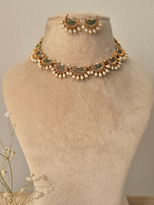 Gold jewelry design half-moon with small green stones in middle and pearls attached outside and same design earrings by naitri.in