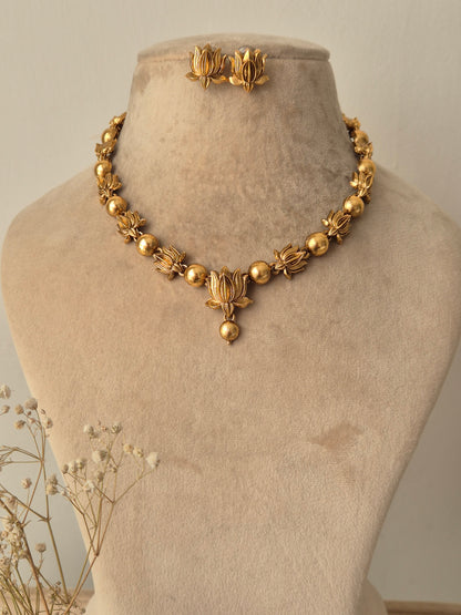 Handcrafted golden brass alloy necklace with traditional floral motifs and matching stud earrings, By naitri.in