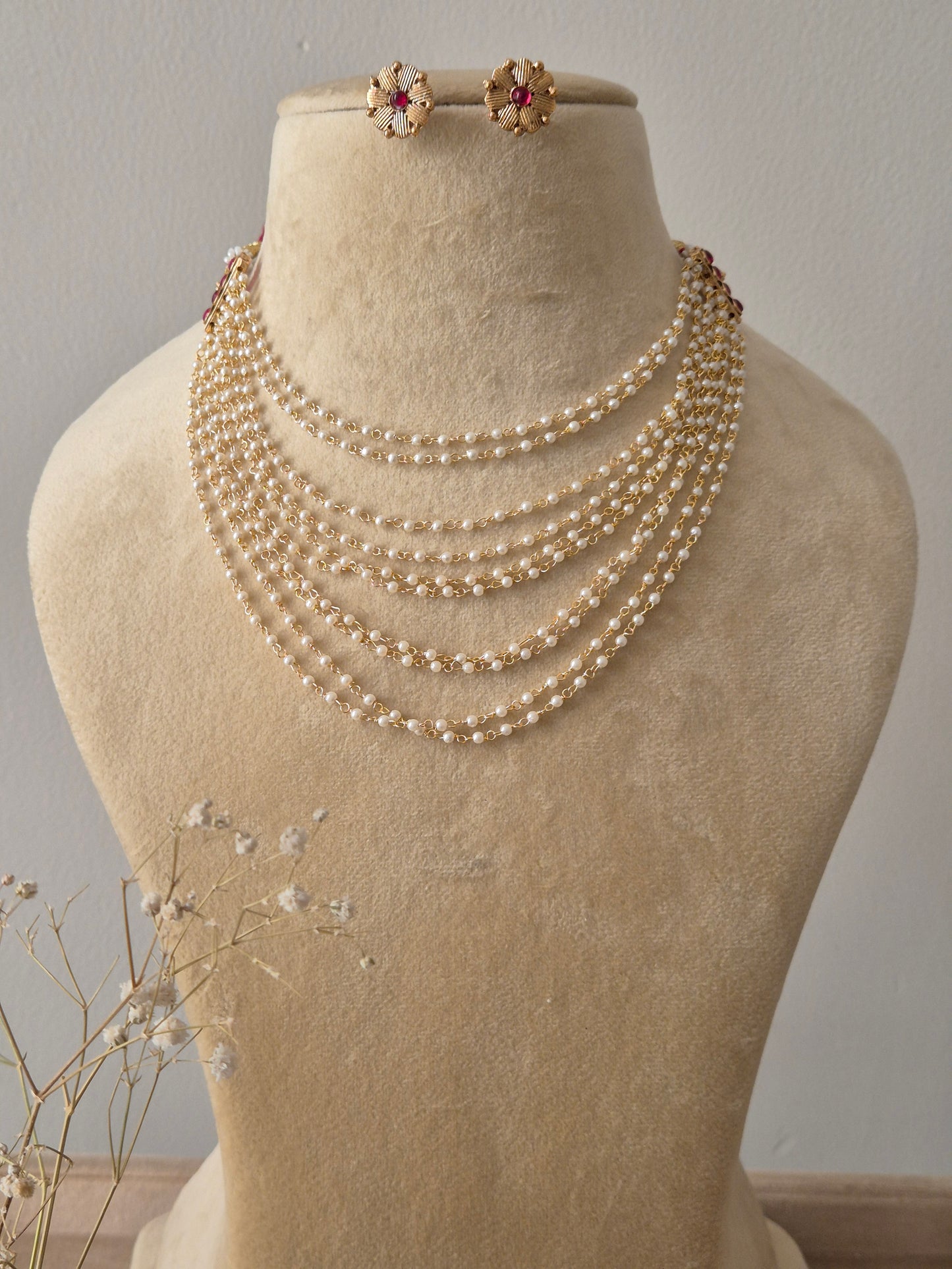 Multilayered white pearl strand necklace  with red gemstone accents and matching floral stud earrings by natri.in