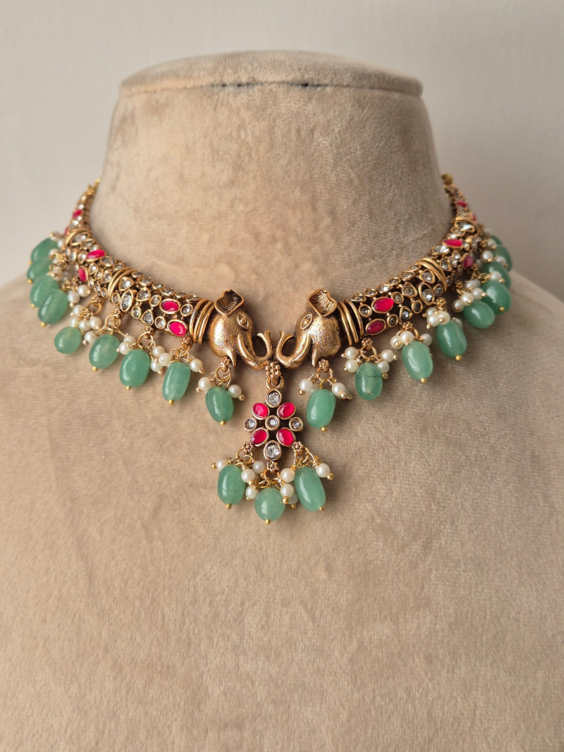 Handcrafted Hasmita gold-toned necklace set with floral pink stone accents and green beads by naitri.in