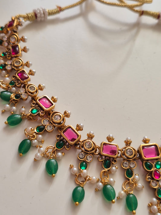 Traditional Indian Hasrat necklace and earring set with red and green stones pearls and green oval beads hanging down from the neckpiece by naitri.in