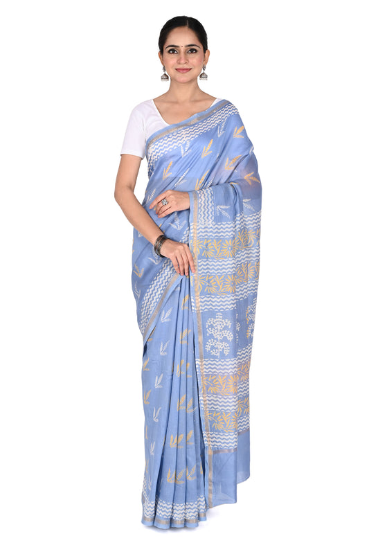 A woman wearing a light blue Hazel hand block printed cotton-silk saree with white and gold floral motifs, paired with a white short-sleeved blouse  by naitri.in