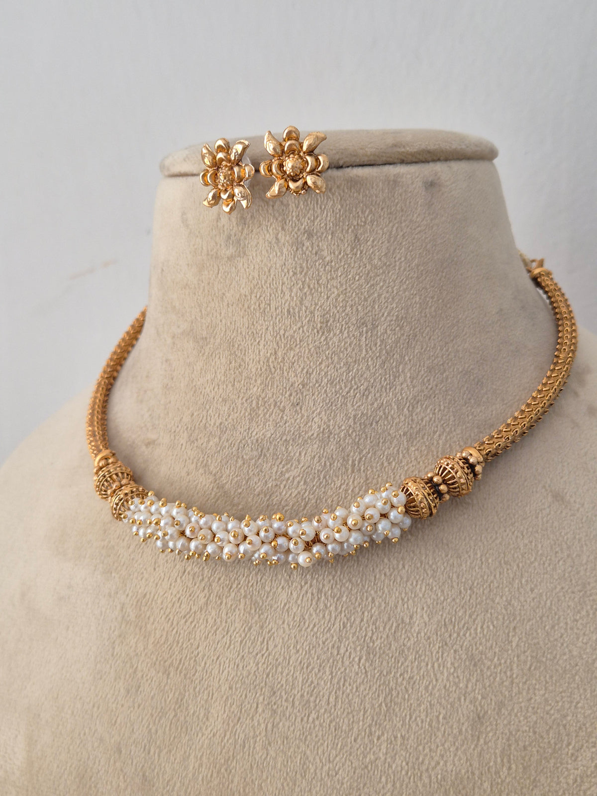Handcrafted brass alloy ethnic necklace featuring an intricate gold chain design, central pearl cluster detailing, and matching stud earrings by Naitri.in