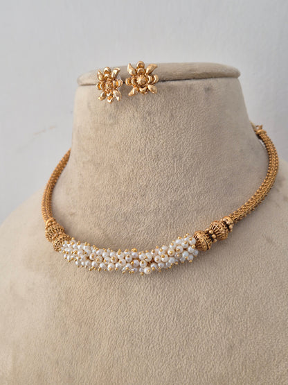 Handcrafted brass alloy ethnic necklace featuring an intricate gold chain design, central pearl cluster detailing, and matching stud earrings by Naitri.in