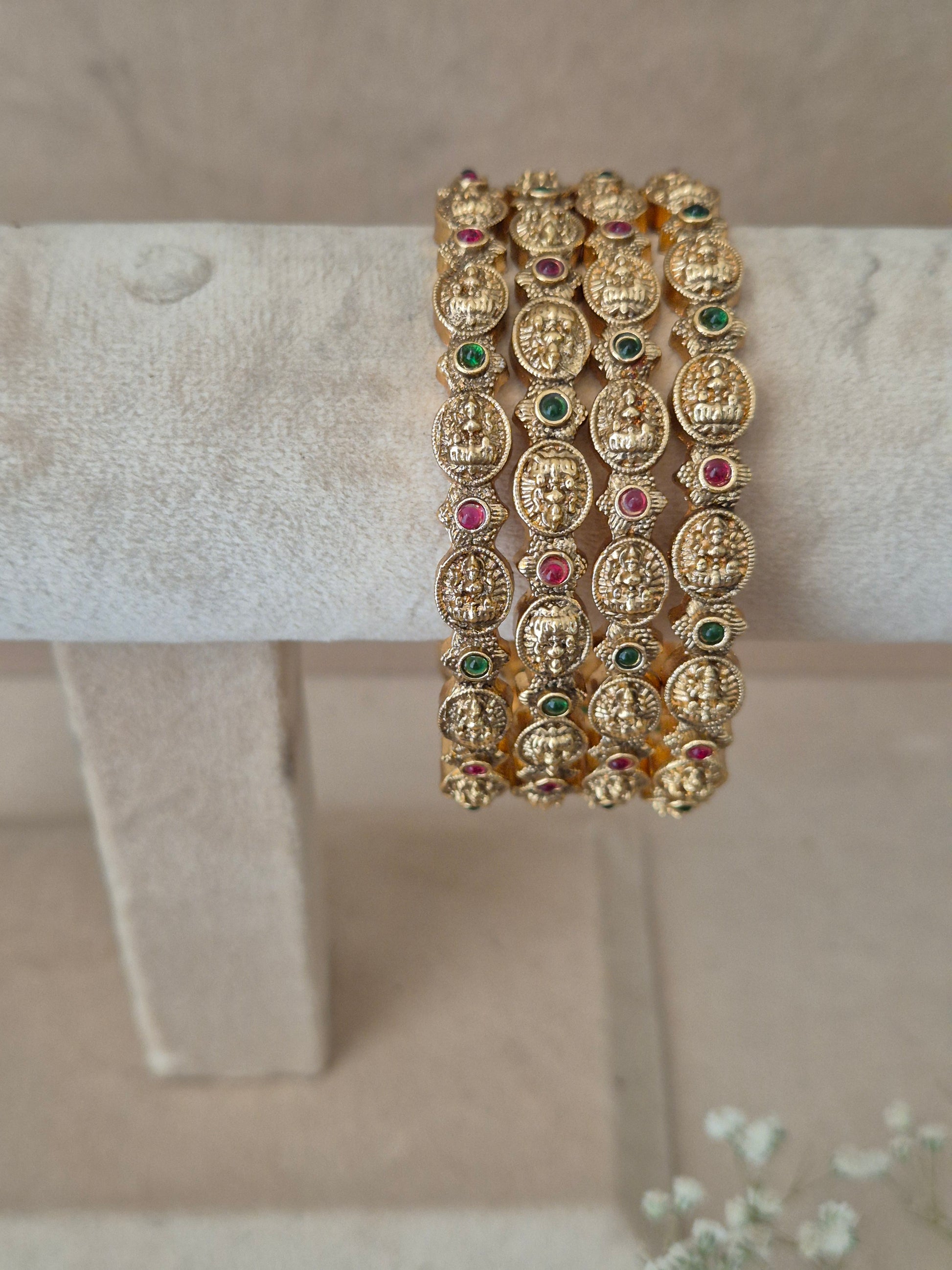Gold bracelet with embedded gemstones, Set of four traditional gold-toned festive bangles with red and green gemstones by naitri.in