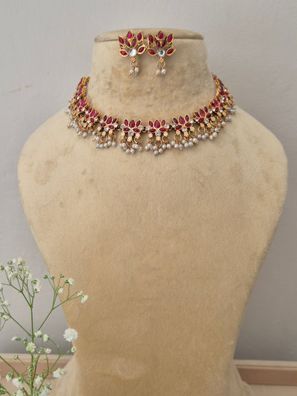 Hemangini Necklace Set by Naitri: A gold-plated ethnic choker necklace featuring a row of leaf-shaped red stones with hanging pearl clusters with matching stud earrings by naitri.in