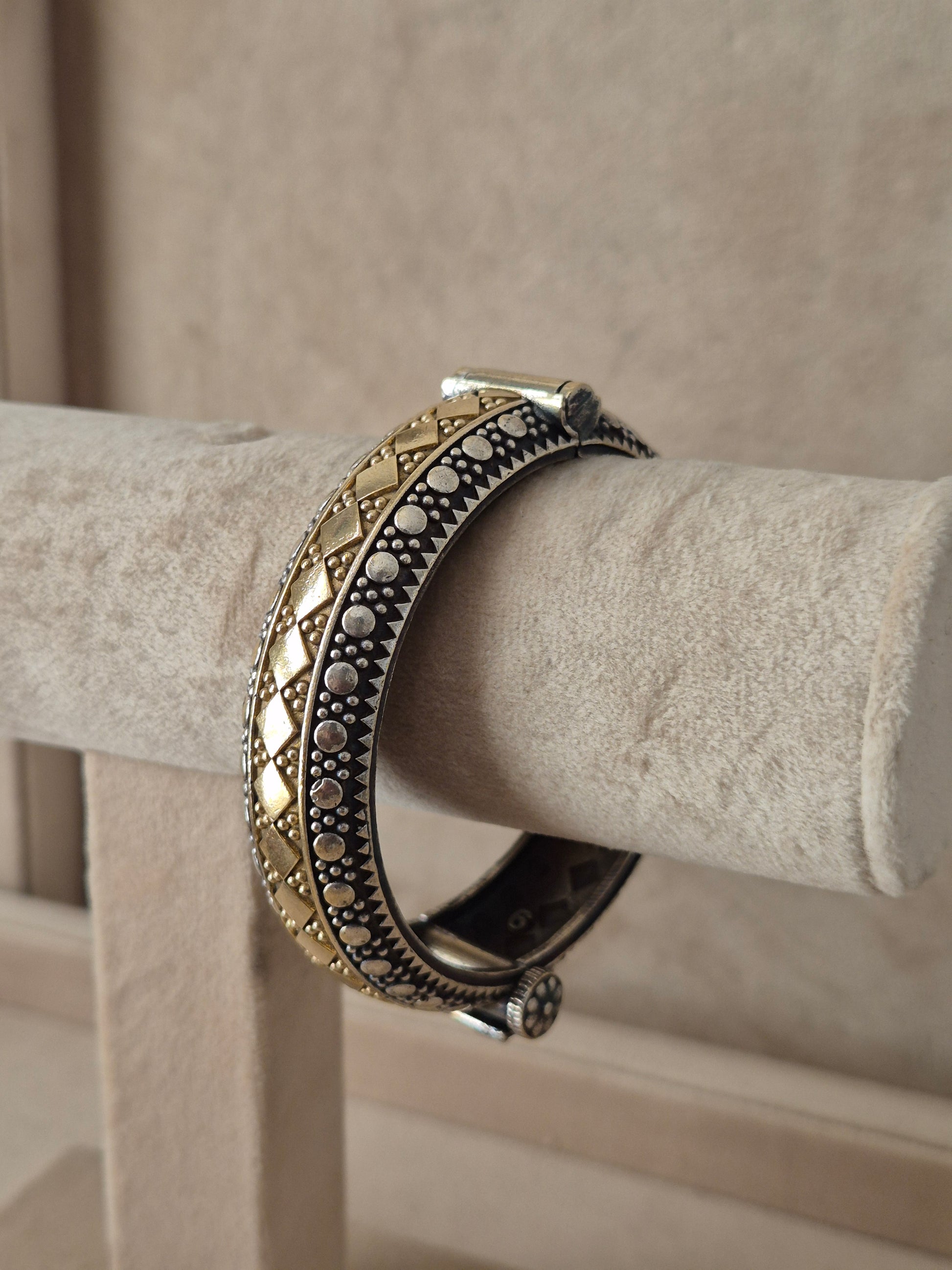 Festive style silver and gold textured bangle bracelet exhibited