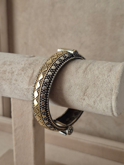 Festive style silver and gold textured bangle bracelet exhibited