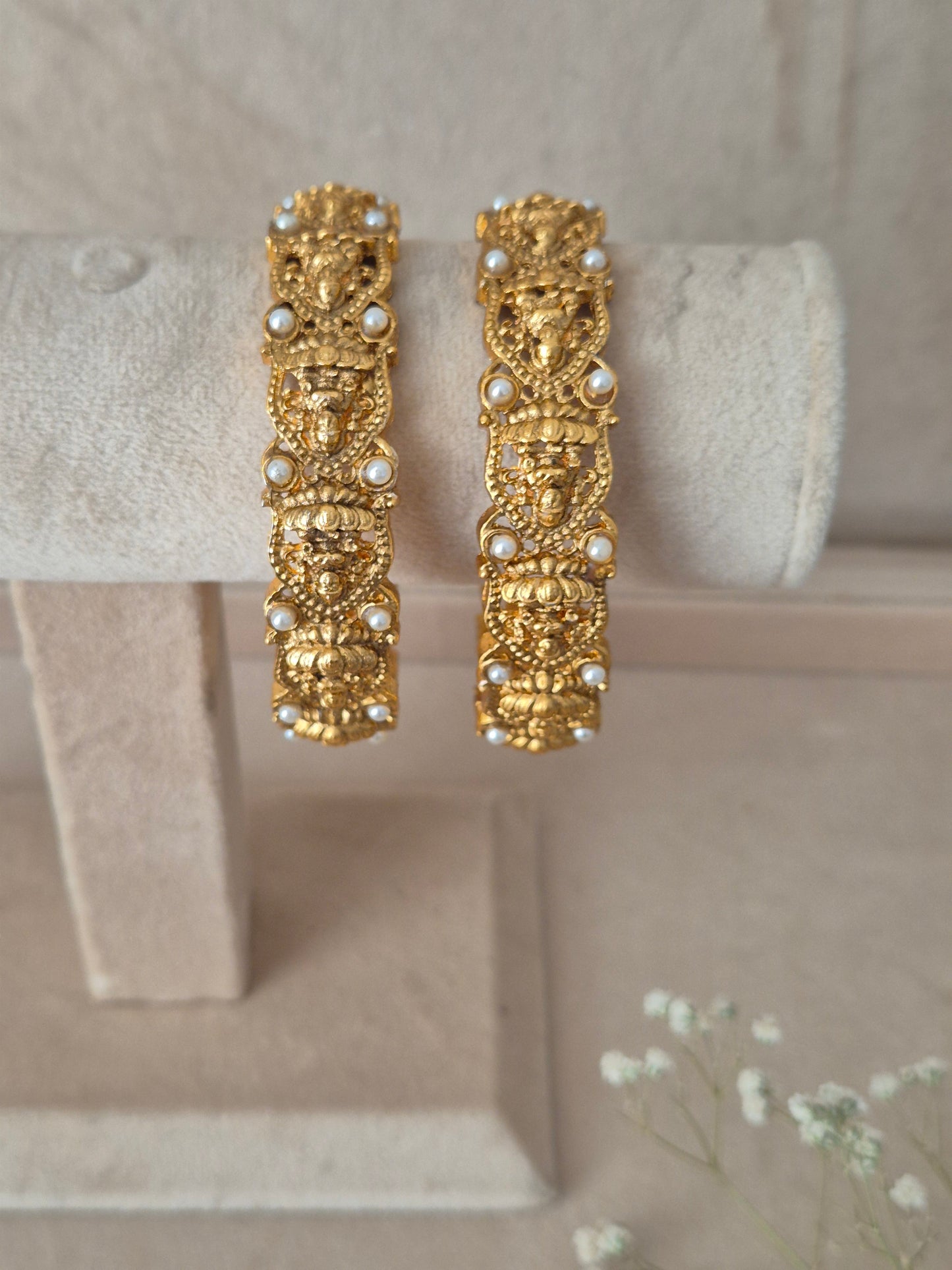 Set of two traditional gold-toned festive bangles with tiny white pearl accents. by naitri.in