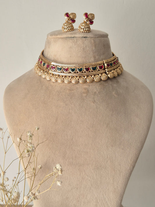 Handcrafted gold-plated brass choker necklace with intricate red-green stone embellishments and matching jhumka earrings by naitri.in