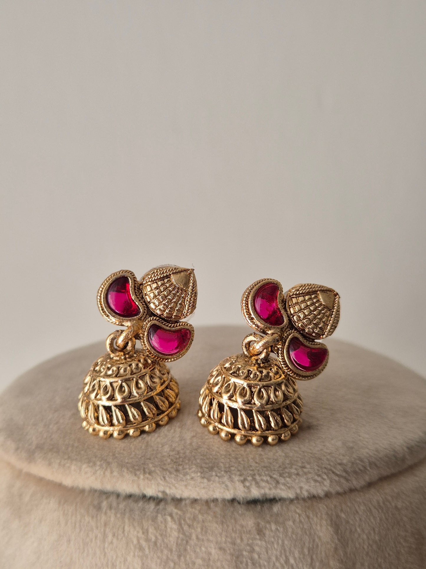 Antique gold earring set with ruby-colored stone accents by naitri.in