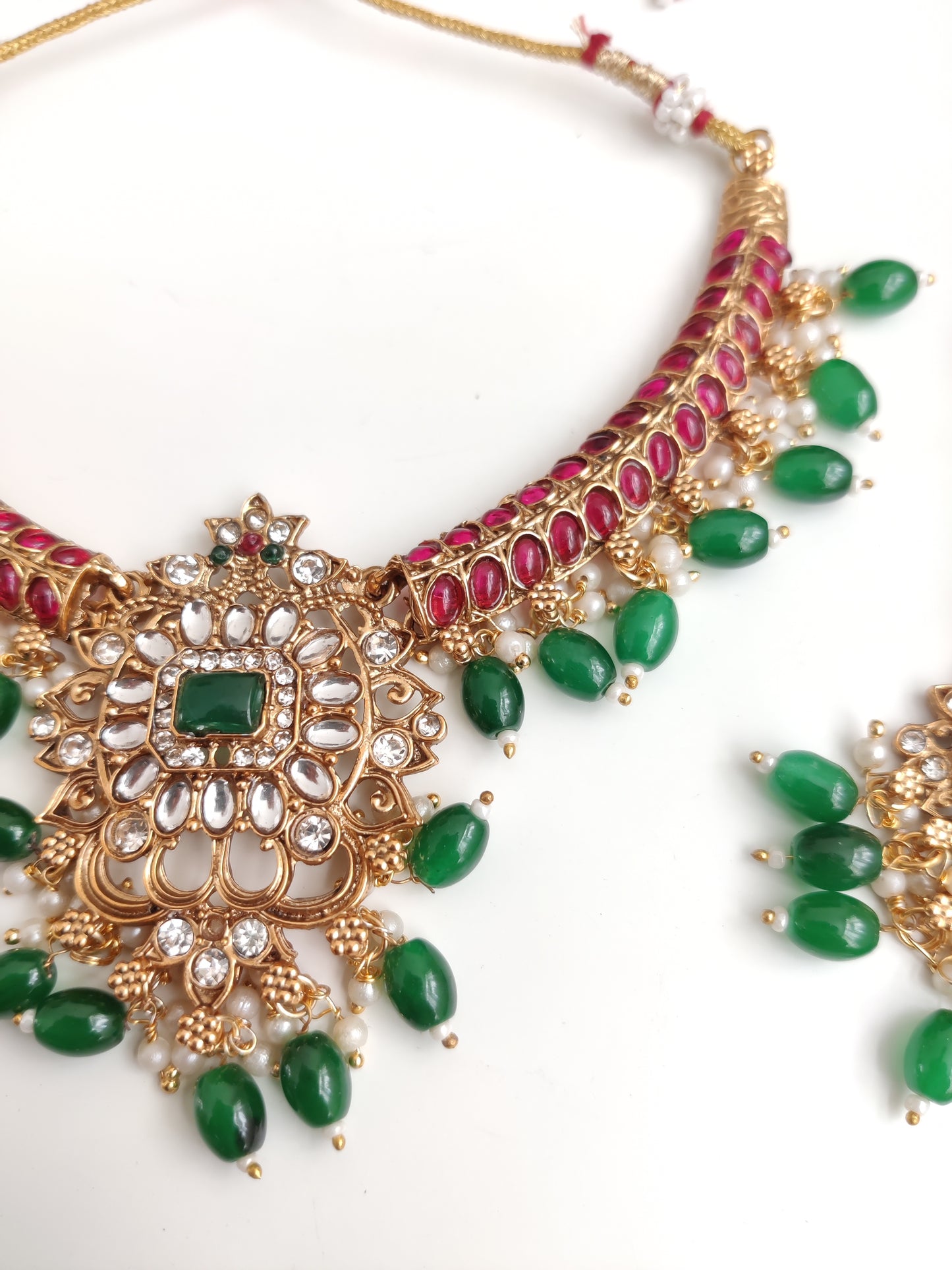 Premium temple necklace set with rich gold, green, and red details photographed on neutral background