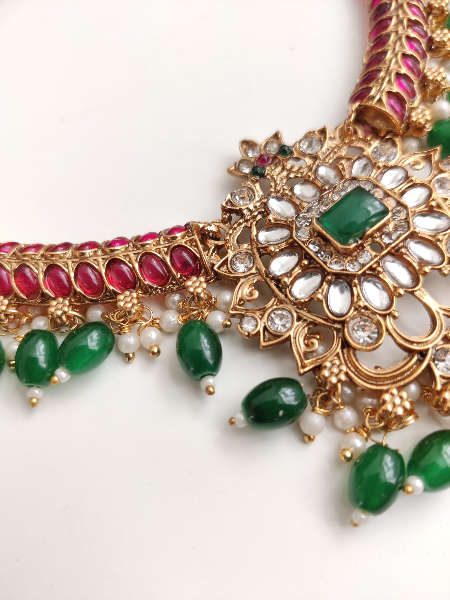 Premium temple necklace set with rich gold, green, and red details photographed on neutral background