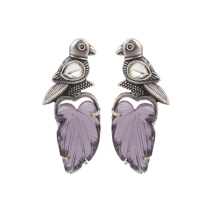 Purple stud earrings with stonework, displayed on a jewelry stand