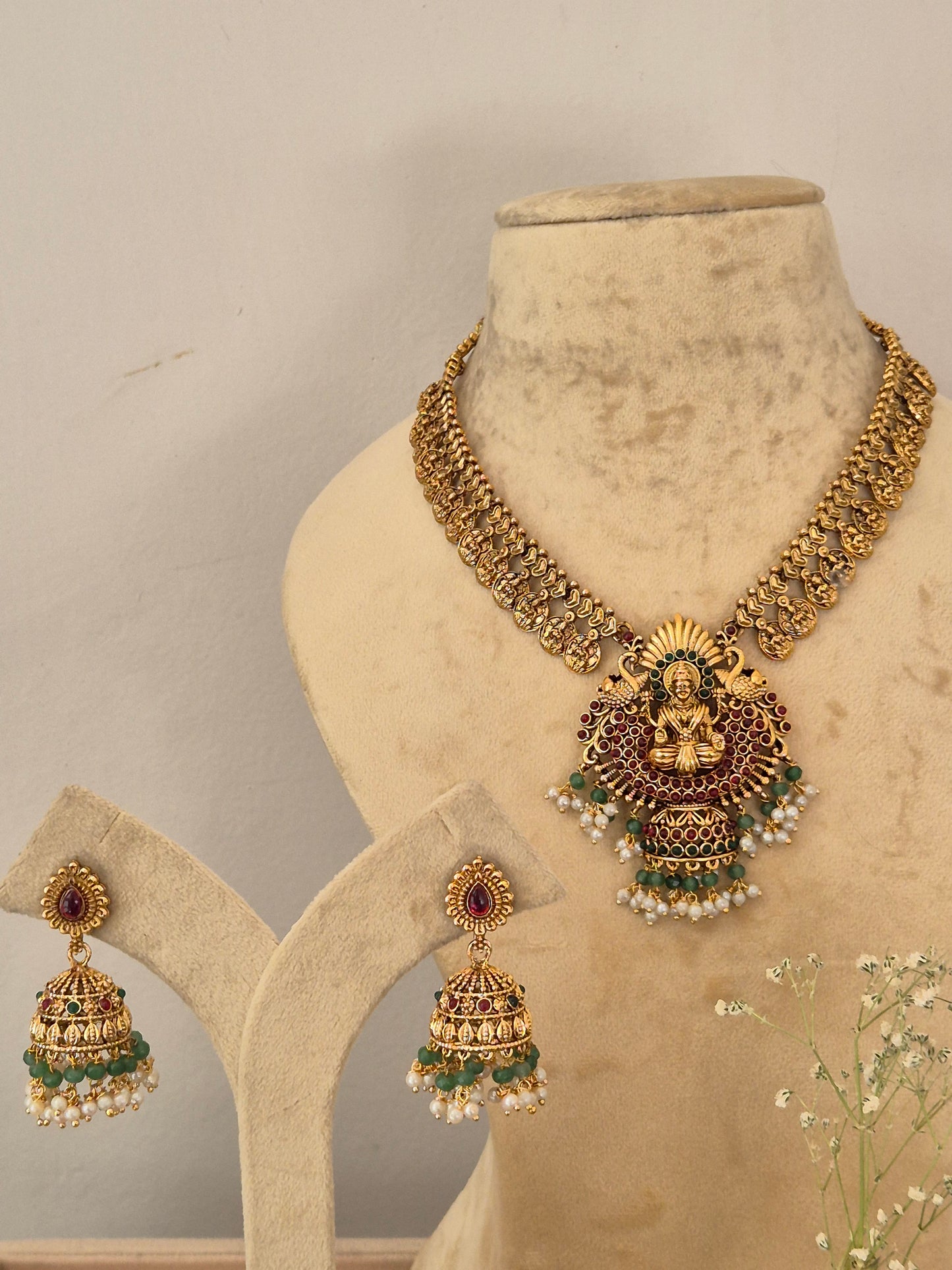 Gold-toned traditional Indian jewelry set featuring a necklace, earrings, and a matching earrings by naitri.in