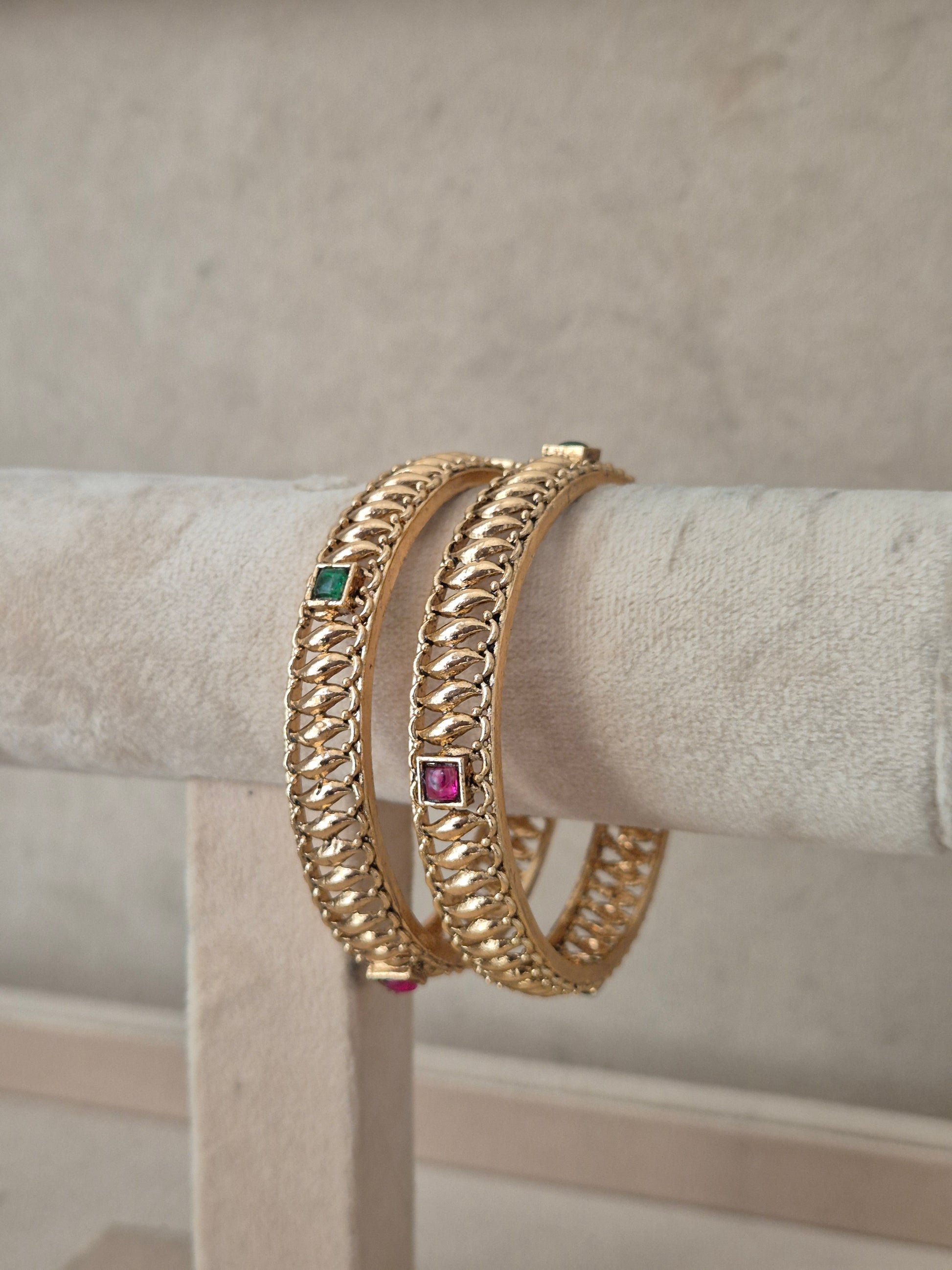 Two gold-plated chain-link bangles with small square green and pink gemstone accents, by naitri.in