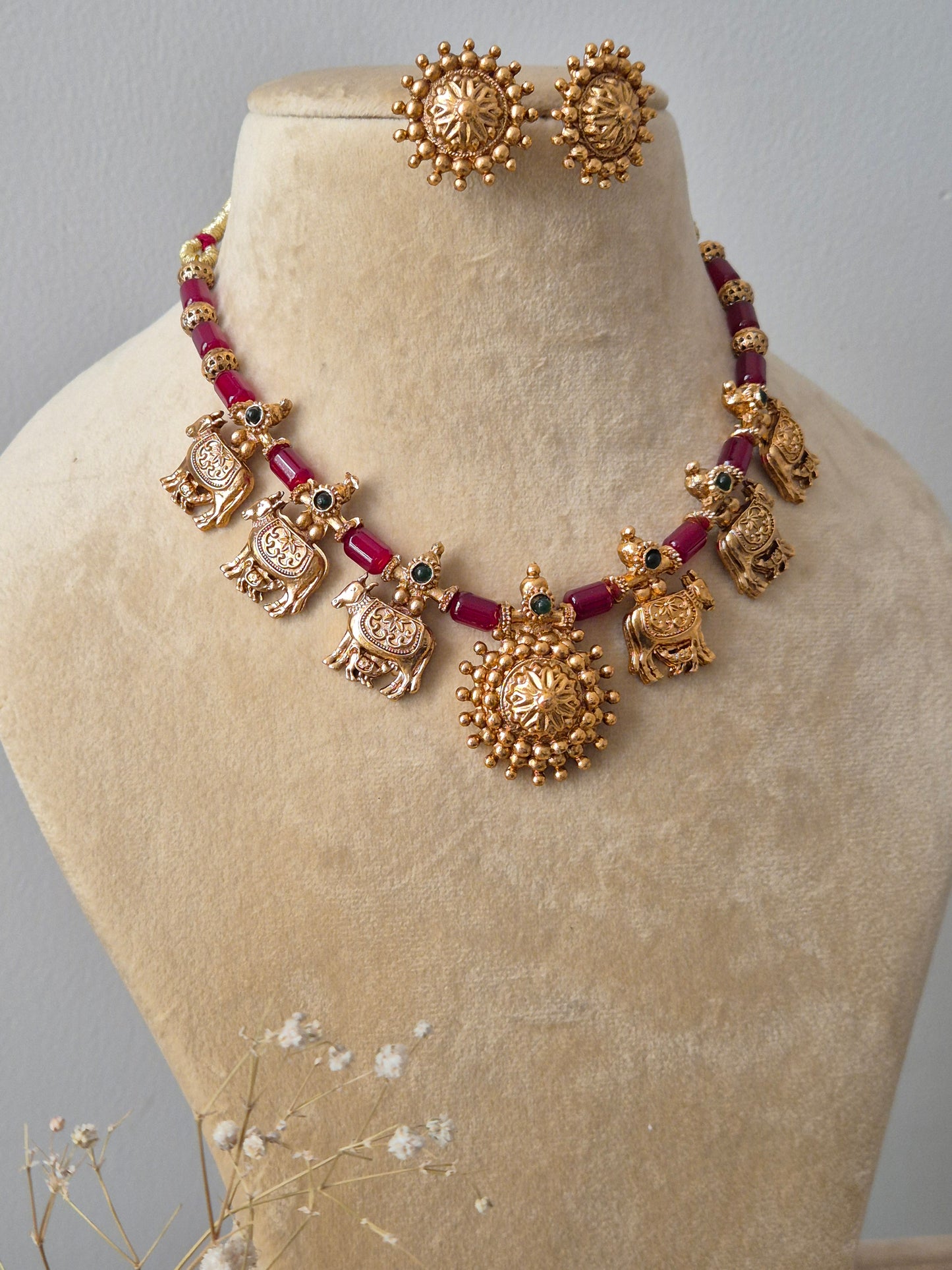 Handcrafted Indian ethnic necklace set with gold-toned bird charms and red bead spacers, featuring a large circular pendant and matching textured stud earring  by naitri.in
