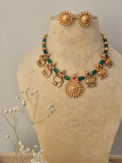 Handcrafted Indian ethnic necklace set with gold-toned mother ccow charms and green bead spacers, featuring a large circular pendant and matching textured stud earring  by naitri.in