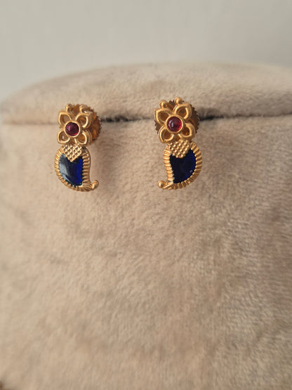 A pair of gold-toned traditional earrings with dark blue enamel paisley motifs and small red gemstone accents, by naitri.in
