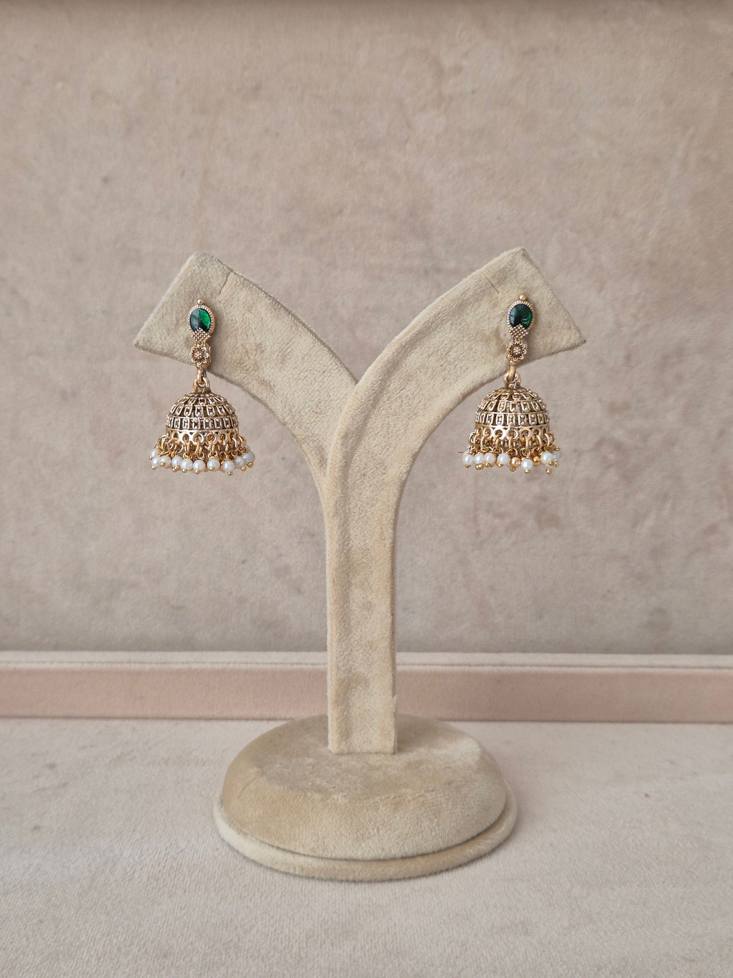 A pair of traditional Indian gold jhumka earrings with green stone accents and white pearl bead drops, by naitri.in
