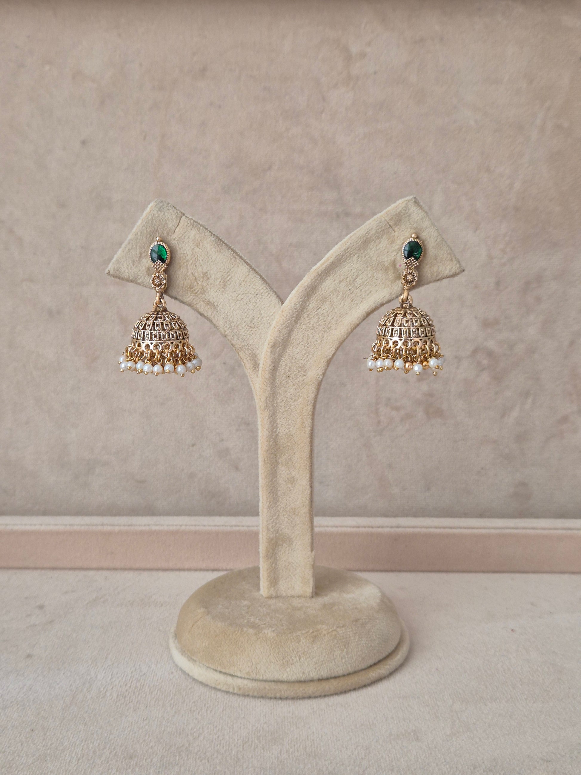 A pair of traditional Indian gold jhumka earrings with green stone accents and white pearl bead drops, by naitri.in